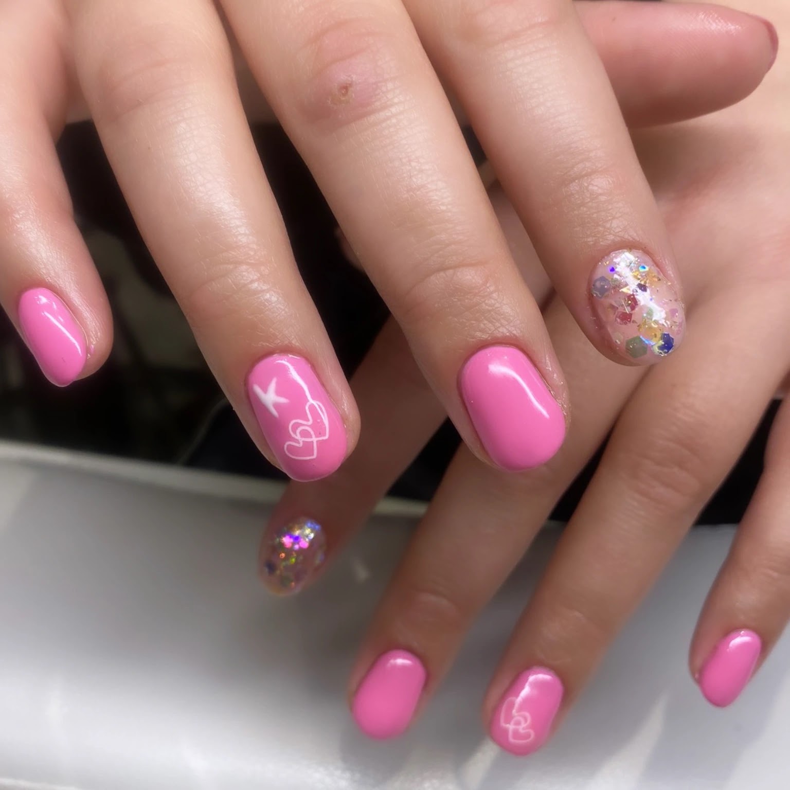 Roze nagels met hartjes, een sterretje en glitter